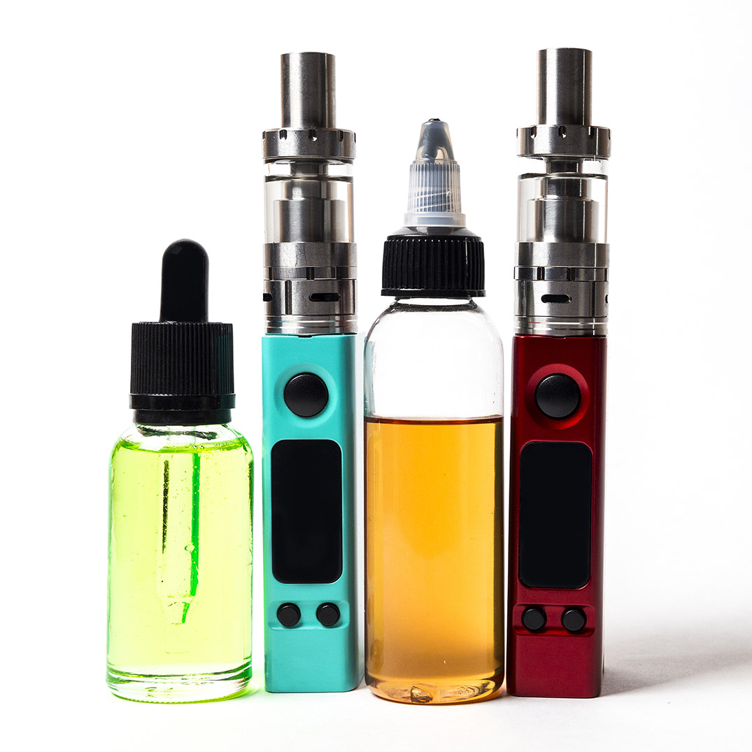 e- liquid, e-juice in the bottles and e-cigarette (vape) isolated on the white background with copyspace